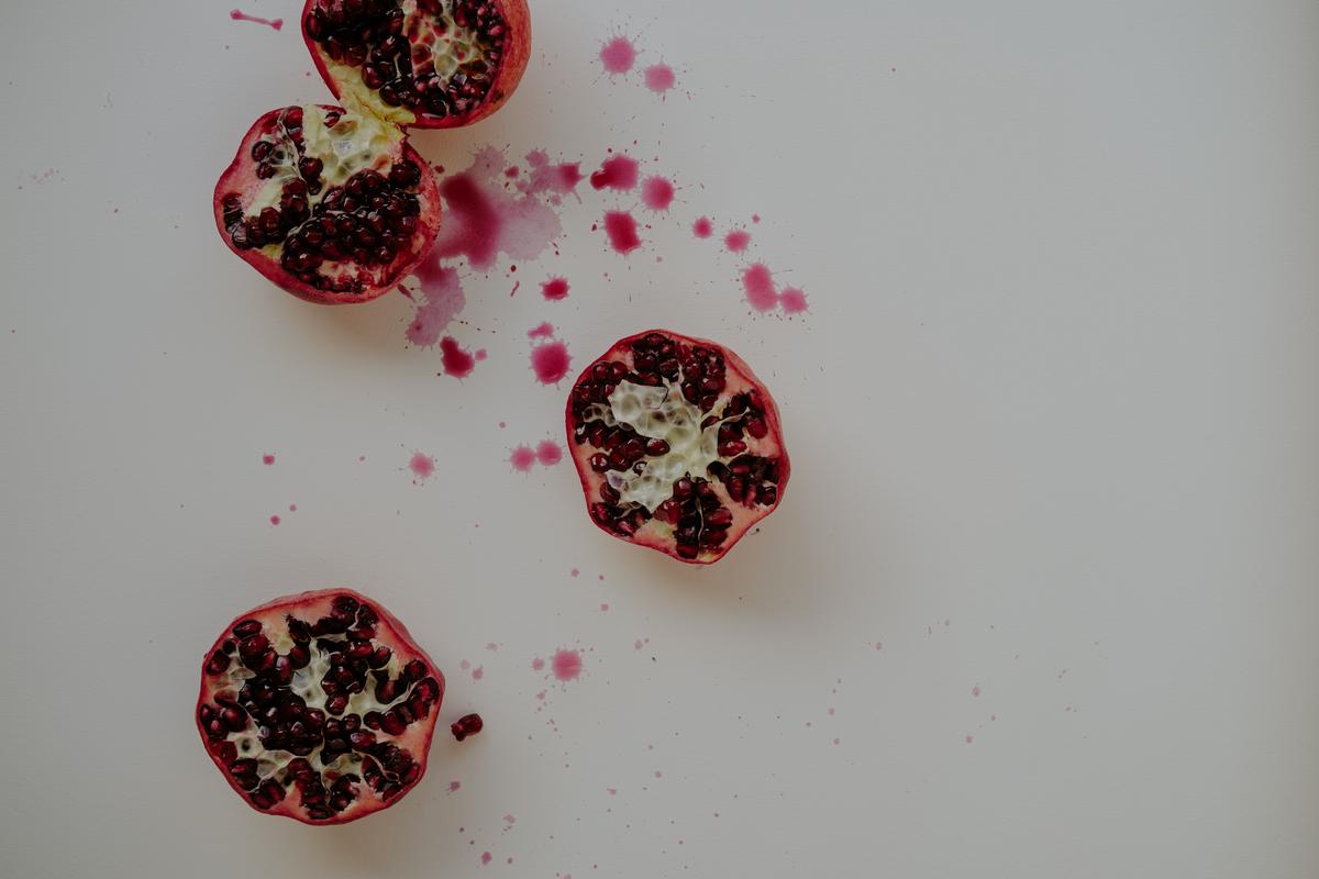 Image description: A hand holding a bowl of pomegranate seeds with water droplets on them, ready for planting