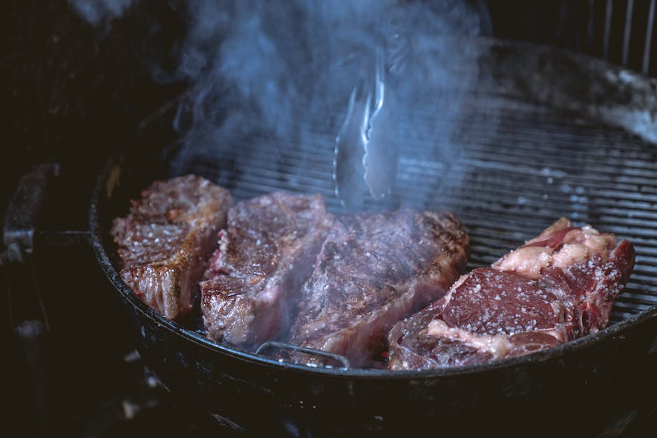A close-up image of a ribeye steak cooking on a grill