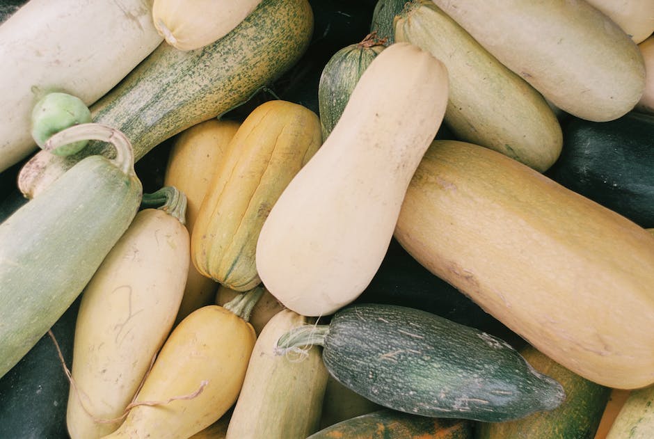 Image of a ripe spaghetti squash displayed in a wooden bowl, showcasing its deep golden yellow color and unique flesh separated into spaghetti-like strands.